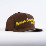 Brown trucker cap with yellow Carter Country stitch and Ten Sleep in native american symbols