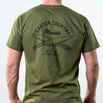 Rear modeled view of olive tee Carter Country Meats text above two crossed knives with ten sleep in native american symbols below
